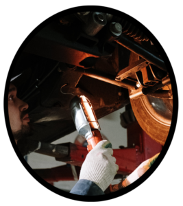 An automobile mechanic inspecting the brake system from the underside of a car