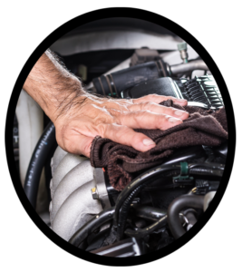 An automobile mechanic cleaning the top of an engine after service