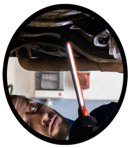 A mechanic examining the resonator of an automobile exhaust system